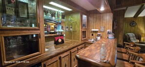 A wooden bar area with a coffee machine, hand sanitizer, and a clock on the wall.