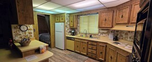 A compact kitchen with wooden cabinets, a refrigerator, a sink, and a countertop with various appliances.