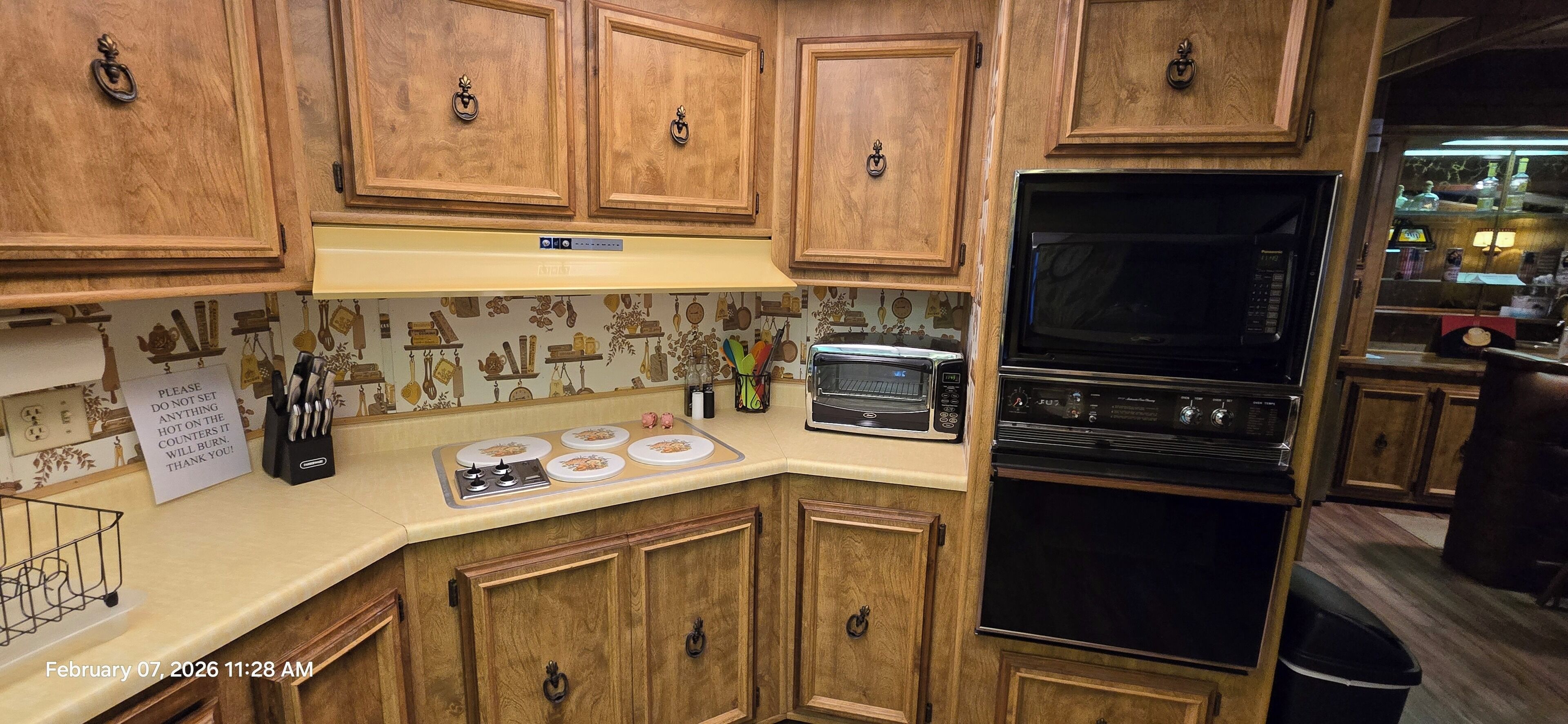 A kitchen with wooden cabinets, a microwave, a toaster, and a stove.