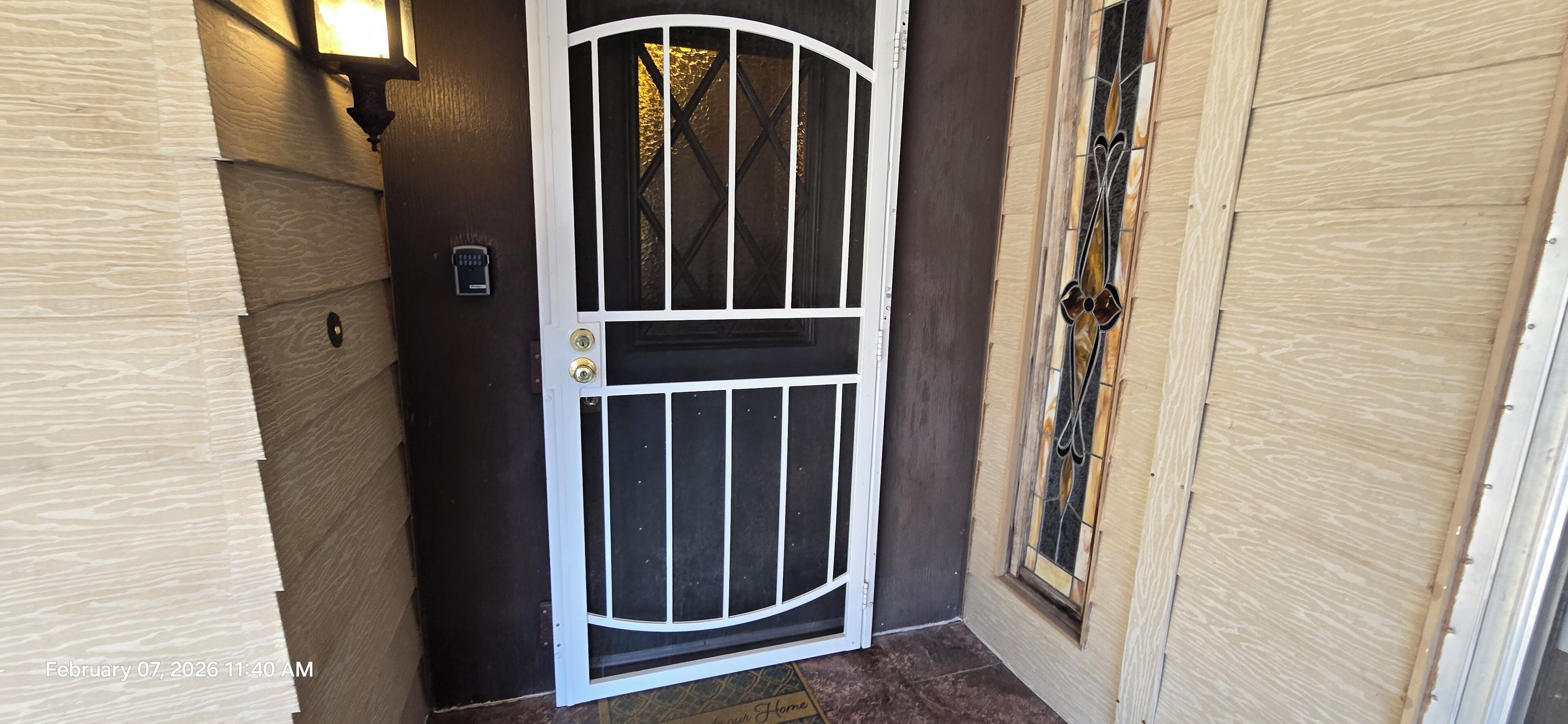A door with a white frame and a glass panel, a wall-mounted light, and a wooden door frame with a glass window.