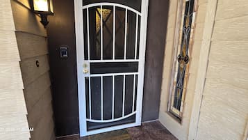 A door with a white frame and a glass panel, a wall-mounted light, and a wooden door frame with a glass window.