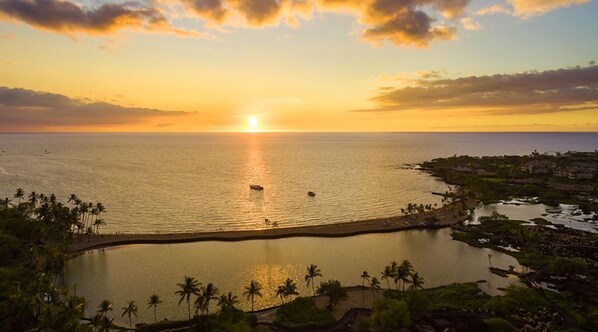 Un resort costero con playa, un puerto deportivo y una pequeña isla con palmeras.