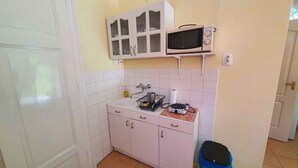 A compact kitchen with white cabinets, a microwave, and a sink. - Studio near the beach with internet (Siófok)