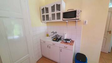A compact kitchen with white cabinets, a microwave, and a sink.