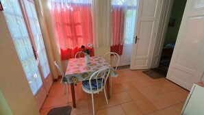 A dining area with a table and chairs, a vase with flowers, and a door leading to another room. - Studio near the beach with internet (Siófok)