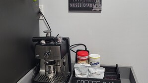 Un espacio de cafetería con una máquina de café, un letrero que dice "COFFEE BAR" y una pared decorada con motivos de viajes.