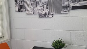 Un comedor con una mesa dispuesta para dos, una obra de arte con temática urbana en la pared y una pequeña planta en maceta sobre la mesa.