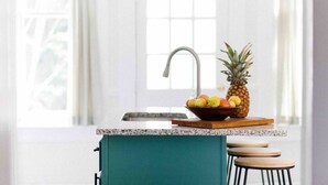 A kitchen with a sink, a bowl of fruit, and a pineapple on a wooden board. - Three king beds. One place for everyone to land. Come back from the tournament, graduation, or family visit, spread out, sleep incredibly well, and wake up ready for Montgomery again. (Montgomery)