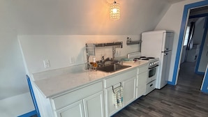 A kitchen with white cabinets, a sink, a stove, and a refrigerator.