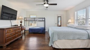 A bedroom with a bunk bed, a flat-screen TV, a dresser, and a window with blinds. - Black Dog Lodge & Fishing Charter- Waterfront! (New Orleans)