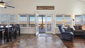 A spacious living room with a dining area, large windows, and a sign reading "BLACK DOG LODGE EST. 2021". - Black Dog Lodge & Fishing Charter- Waterfront! (New Orleans)