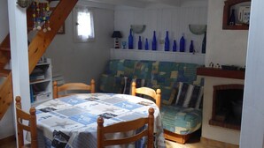 Un coin repas avec une table dressée pour quatre personnes, des chaises en bois et une nappe à motifs.