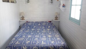 Une chambre à coucher avec une couvre-lit aux motifs marins, des murs blancs et une fenêtre donnant sur un beau paysage.