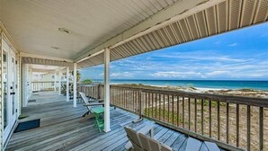 A wooden deck with a view of the beach and ocean.