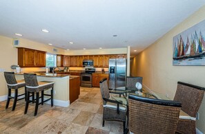 A modern kitchen with wooden cabinets, stainless steel appliances, and a central island with bar stools. - Family Favorite Vacation Destination with Direct Front Gulf Views! ~ OW304 (Indian Rocks Beach)