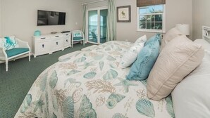 A bedroom with a bed, a TV, a dresser, a chair, and a window with a view. - Tortuga De Mar-Direct Gulf Front, Top Floor, Corner unit with Breathtaking Views & Magnificent Sunsets (Belleair Beach)