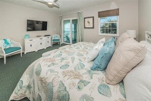 A bedroom with a bed, a TV, a dresser, a chair, and a window with a view.