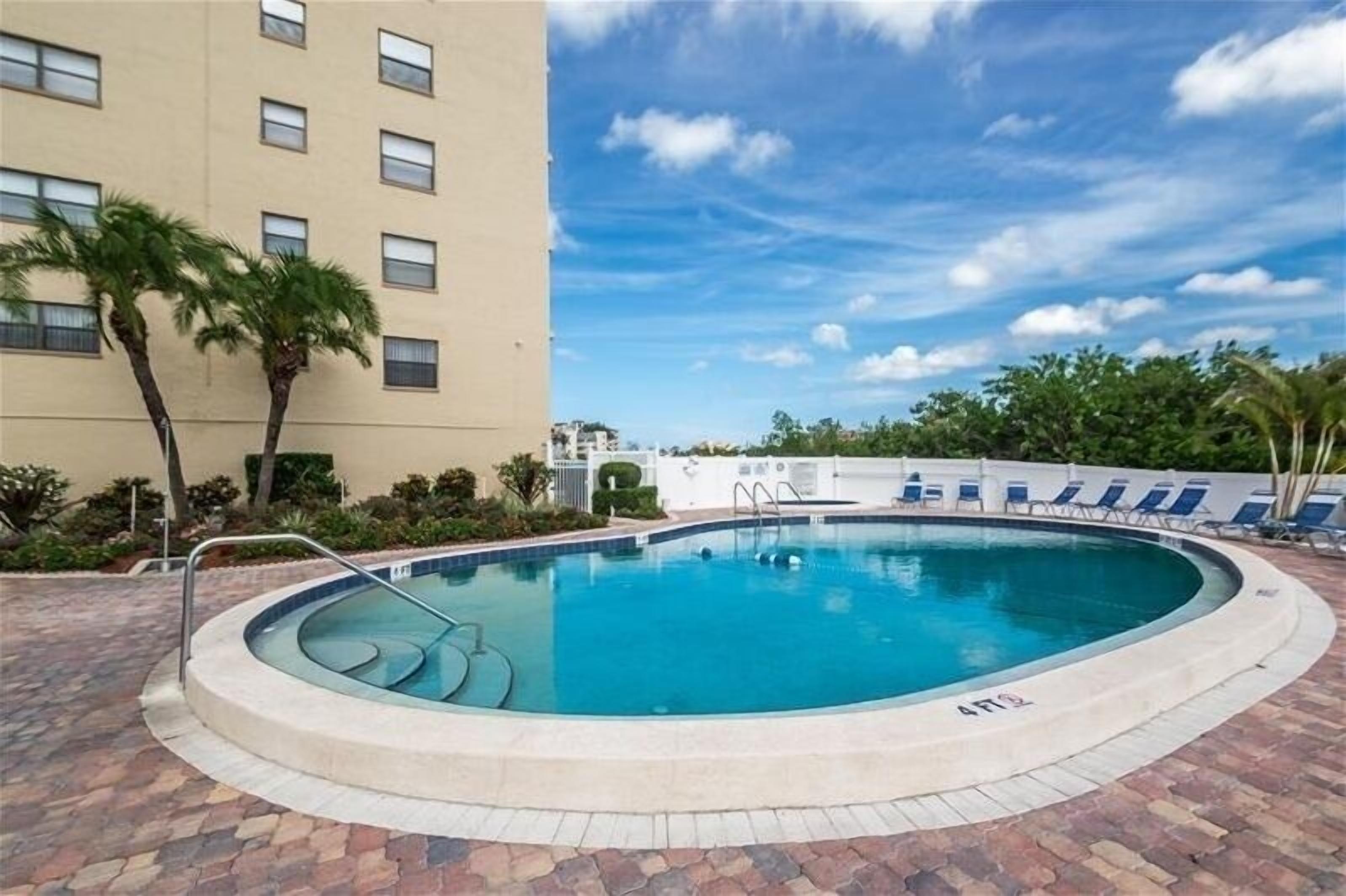 A circular pool with a clear blue water surface, surrounded by a brick walkway.