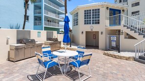 Un patio exterior con una parrilla, asientos y una zona de piscina.
