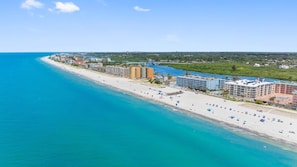 Un hôtel situé sur la côte, avec accès direct à la plage, plusieurs bâtiments et une vue dégagée sur l’océan.