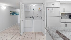 Un lavadero con dos lavadoras, una secadora y un refrigerador.