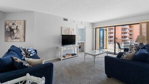 A living room with a TV, sofa, coffee table, and artwork.