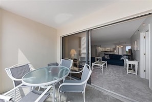 En balkon med et glasbord og stole, en sofa og et TV-møbel.
