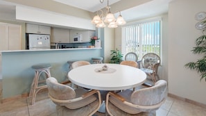 A dining area with a round table, wicker chairs, and a kitchen in the background. - Family Favorite Beach Escape & Hdtv with 200 Channels!~    BP301 (Indian Shores)