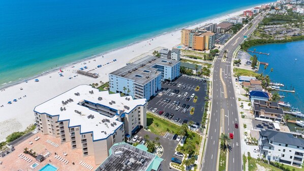 Un hôtel situé sur la côte, avec vue sur la plage, un parking et un port de plaisance.