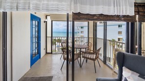 A balcony with a view of the sea, a blue door, and a table with chairs. - Beach Palms Premier Gulf Front 3 bedroom condo steps to the Beach~  BP410 (Indian Shores)