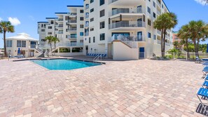 Un hôtel doté d’une piscine, de plusieurs balcons et d’une terrasse en briques.