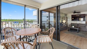 A balcony with wicker furniture, a sliding glass door leading to a living area with a sofa and a coffee table. - Beach Palms Premier Gulf Front 3 bedroom condo steps to the Beach~ BP410 (Indian Shores)