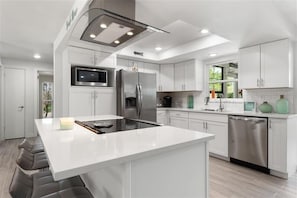 A modern kitchen with white cabinetry, stainless steel appliances, and a central island.