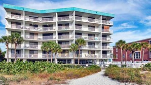 A multi-story hotel with balconies, a sandy pathway leading to the entrance, and palm trees. - Gulf Front Corner Unit & Million Dollar Views~ Chb305 (Madeira Beach)