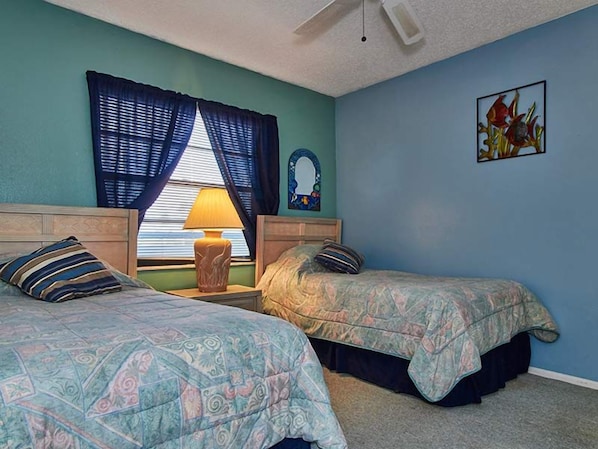 Un dormitorio con dos camas, una ventana con cortinas, una lámpara, un espejo y un cuadro en la pared.