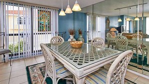 A dining area with a glass-top table, wicker chairs, and hanging pendant lights. - Gulf Front Corner Unit & Million Dollar Views~ Chb305 (Madeira Beach)