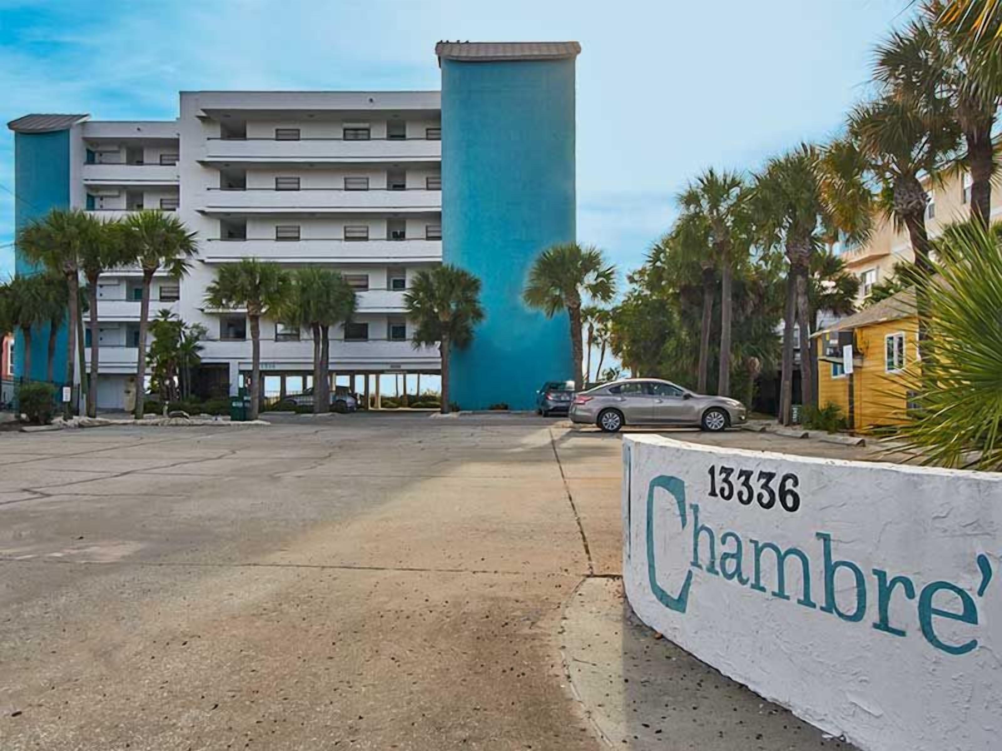 A hotel with a large blue cylindrical structure, a parking lot, and palm trees.