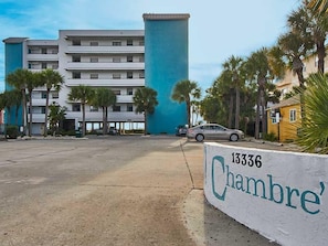 Un hotel con una gran estructura azul cilíndrica, un estacionamiento y palmeras.