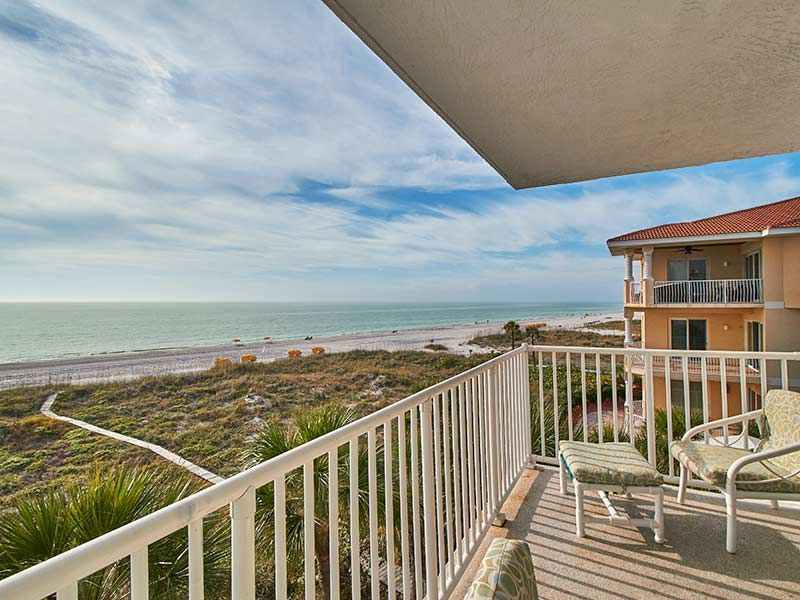 A balcony with a view of the beach and ocean.