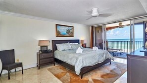 Une chambre à coucher avec un lit, des tables de chevet, une chaise, un tableau et un balcon avec vue.