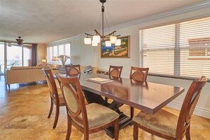 Un coin repas avec une grande table en bois, six chaises et un lustre.