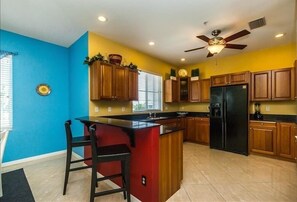 Enjoy cooking in this well-equipped kitchen with a central island, black refrigerator, and wooden cabinets.
