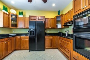 Enjoy cooking in this well-equipped kitchen with a refrigerator, oven, and tiled floor.