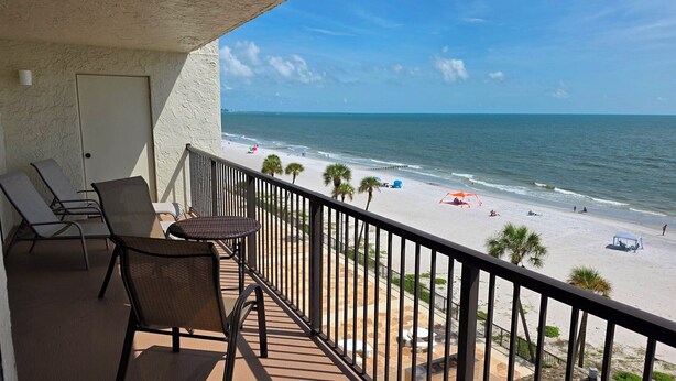 A balcony with a view of a beach, a door, and two chairs. - Tropical Oasis Directly on the Gulf!~  OS608 (Madeira Beach)