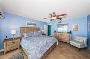 A bedroom with a bed, nightstands, a dresser, a chair, and a ceiling fan.