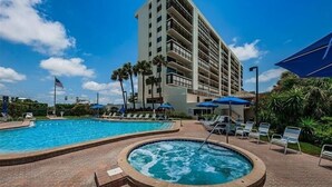A hotel with a large pool area, including a hot tub, surrounded by lounge chairs and umbrellas. - Tropical Oasis Directly on the Gulf!~  OS608 (Madeira Beach)