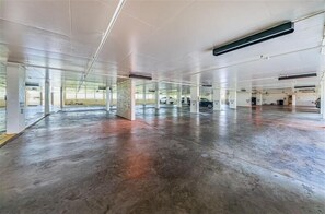 Eine großzügige, leere Tiefgarage mit Betonböden und weißen Säulen.