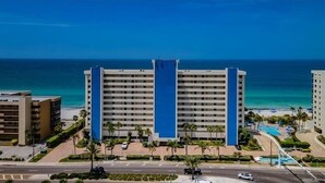A multi-story hotel with a central blue stripe, located near a beach with clear blue waters. - Tropical Oasis Directly on the Gulf!~  OS608 (Madeira Beach)