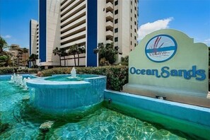 A hotel sign with "Ocean Sands" and a pool area with a fountain. - Tropical Oasis Directly on the Gulf!~  OS608 (Madeira Beach)
