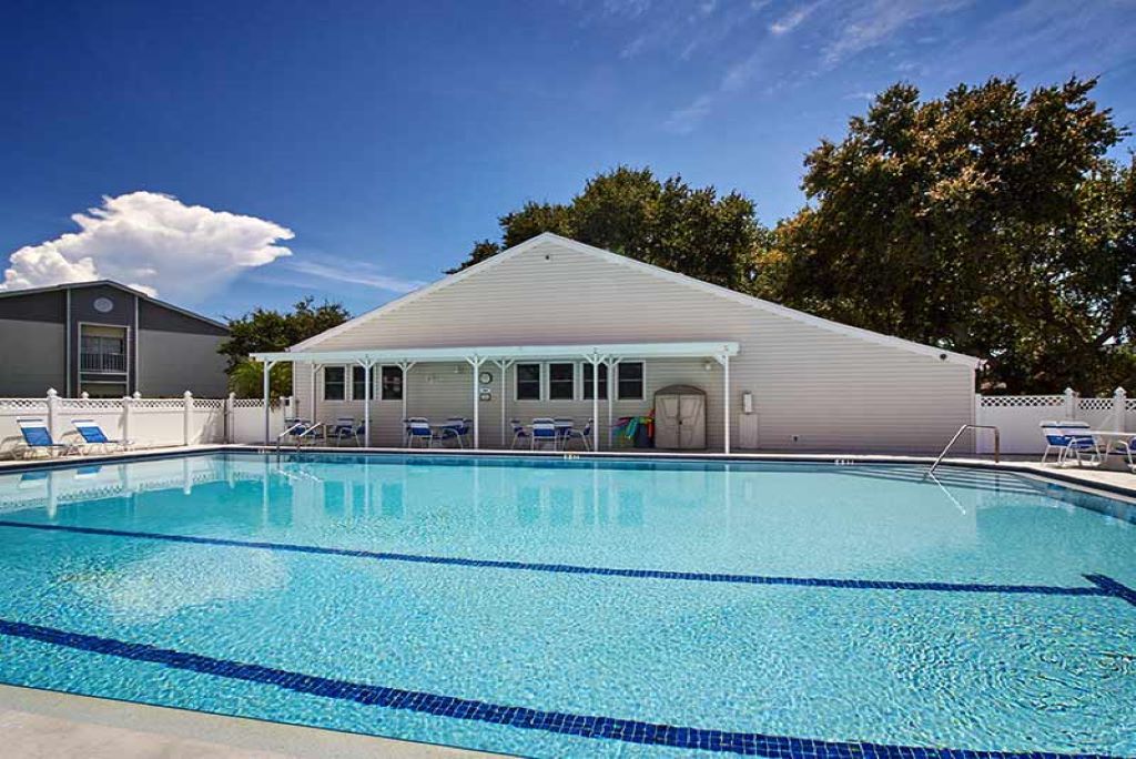 A swimming pool with lounge chairs and a covered patio area.